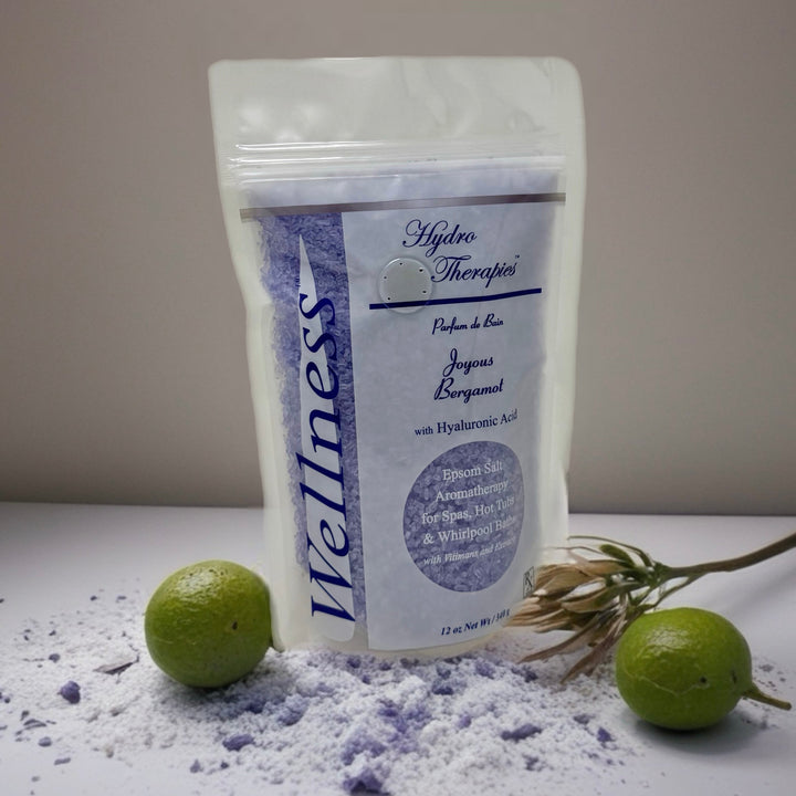 Wellness 12oz Epsom Salt Aromatherapy by Insparation Inc in a white resealable bag with purple salt crystals scattered around and two green limes