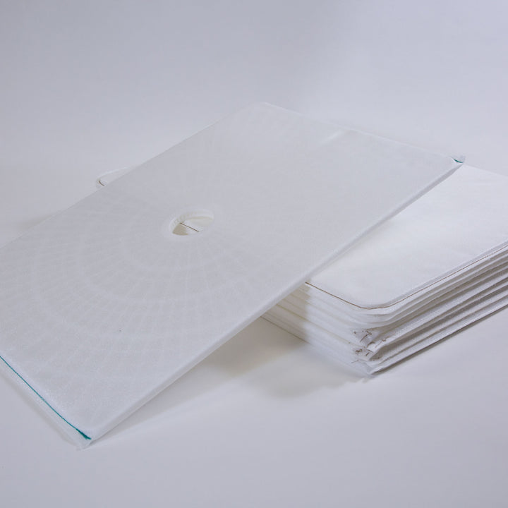 Stack of white rectangular filter grids with one grid positioned on top, featuring a central circular hole