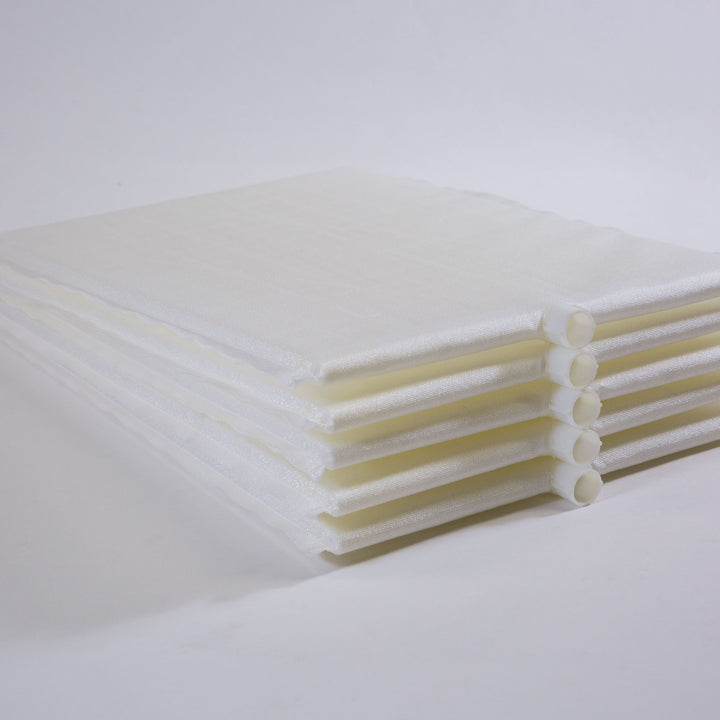 stacked white rectangular filter grids with cylindrical connectors on one side laid on a white surface with a plain white background