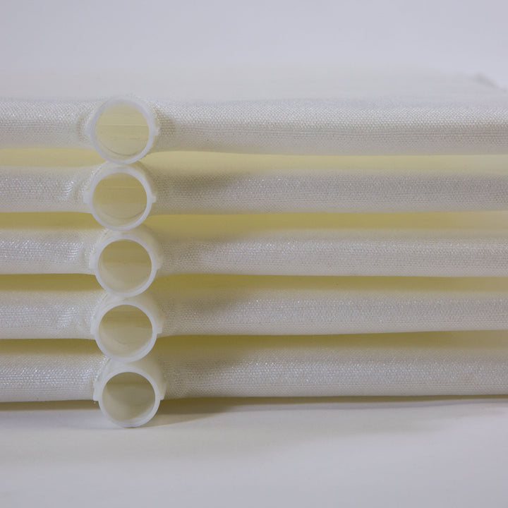 Stack of white cylindrical filter grids with mesh fabric wrapped around plastic frames laid horizontally