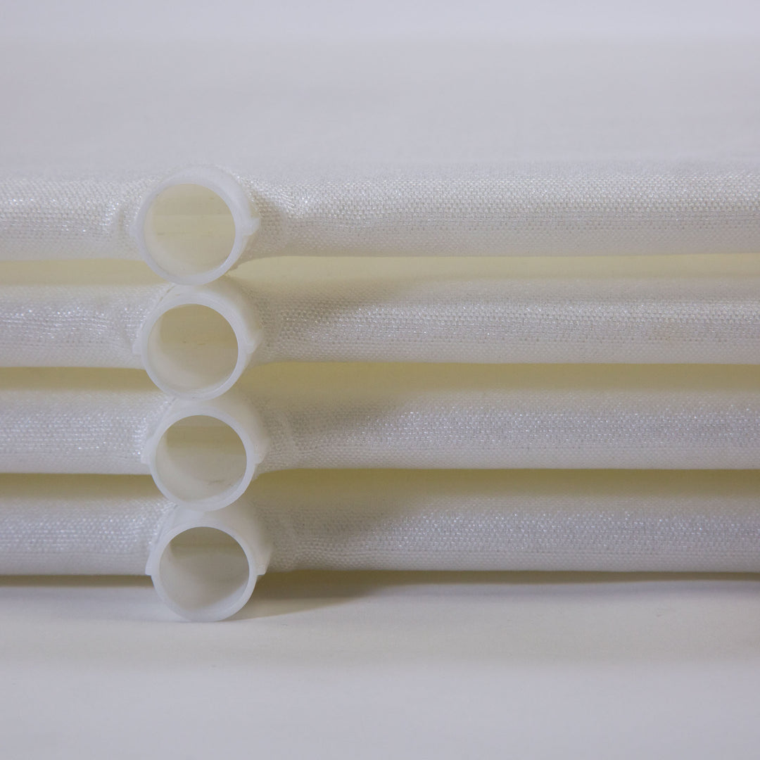 close-up of four stacked white tubular filter grids with hollow plastic ends on light surface and background
