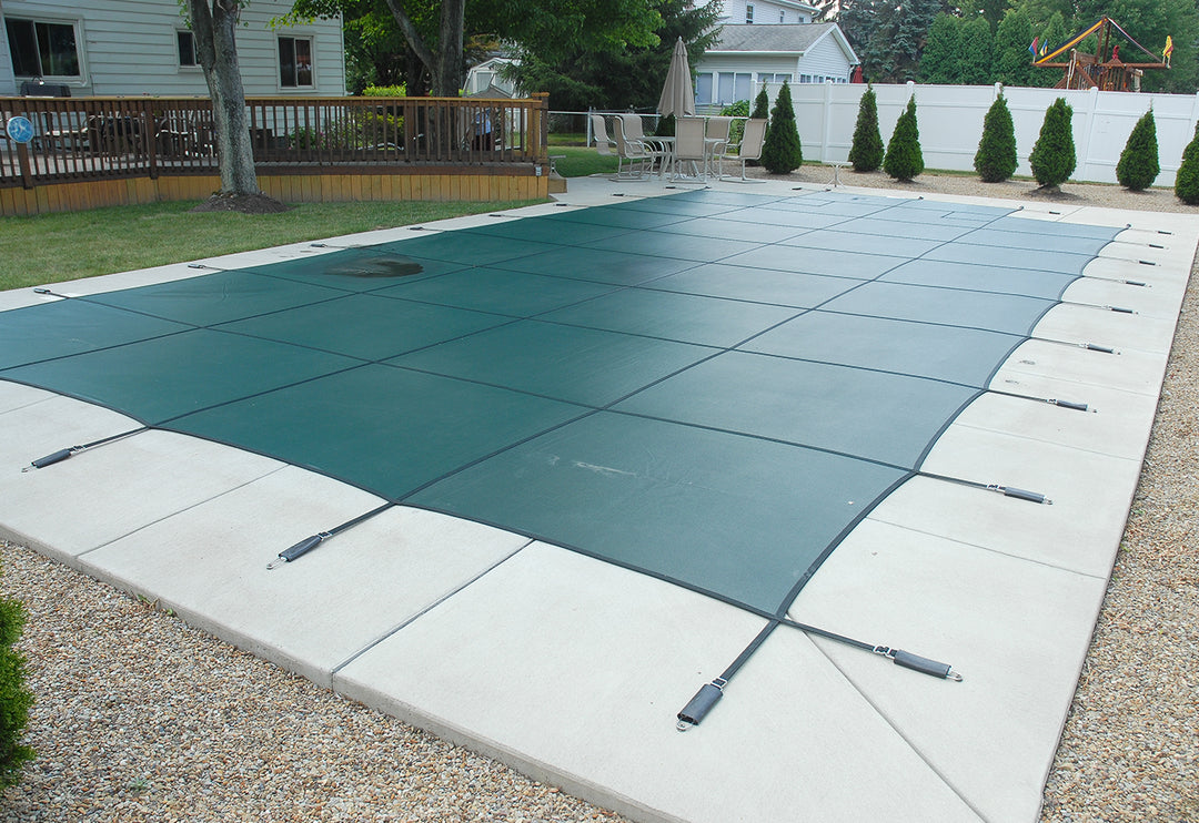 GLI green rectangle mesh safety cover installed on in-ground pool secured with black straps attached to pool deck anchors