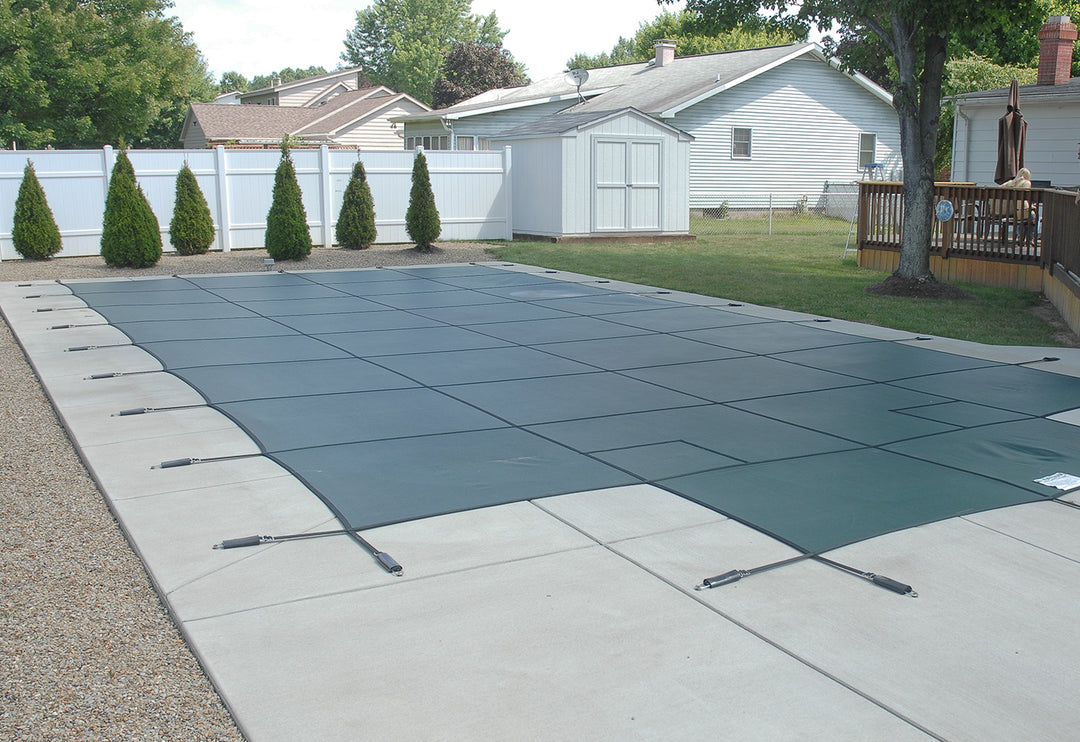 gli 20 foot by 40 foot rectangle green mesh safety cover stretched over inground pool with attached tension springs on concrete pool deck