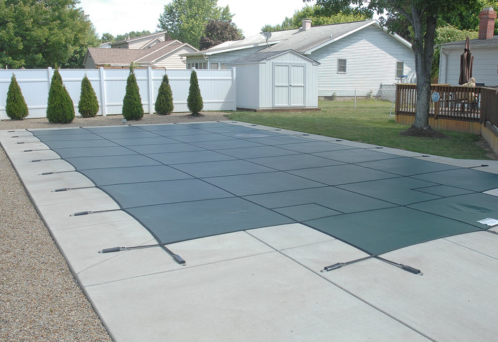 gli 20 foot by 40 foot rectangle green mesh safety cover stretched over inground pool with attached tension springs on concrete pool deck