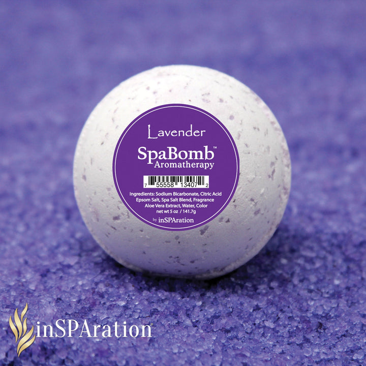 white round inSPAration SpaBomb aromatherapy bath bomb with purple label on a textured purple surface