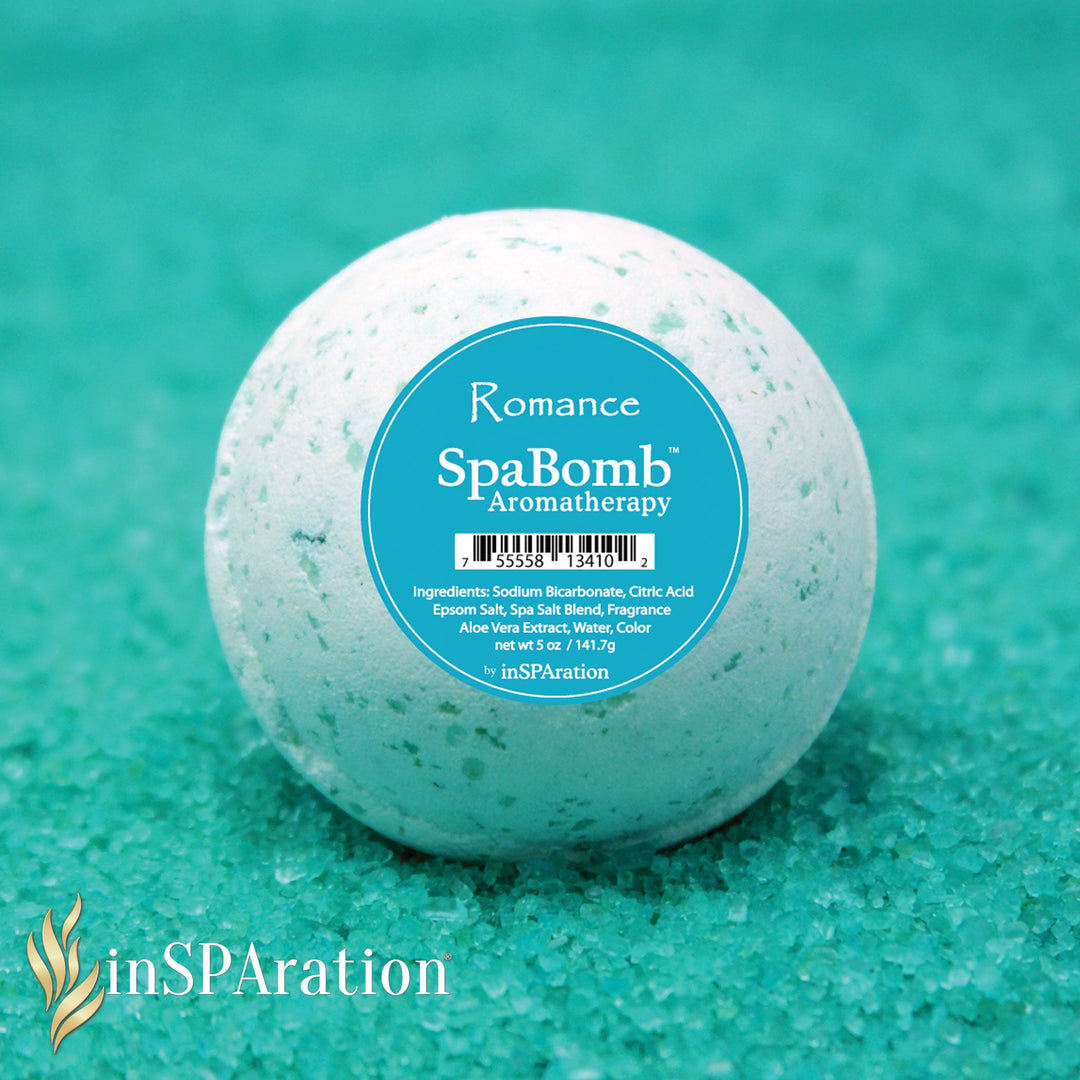 inSPAration SpaBomb Aromatherapy spherical bath bomb with white surface and blue label on turquoise granular bath salt background