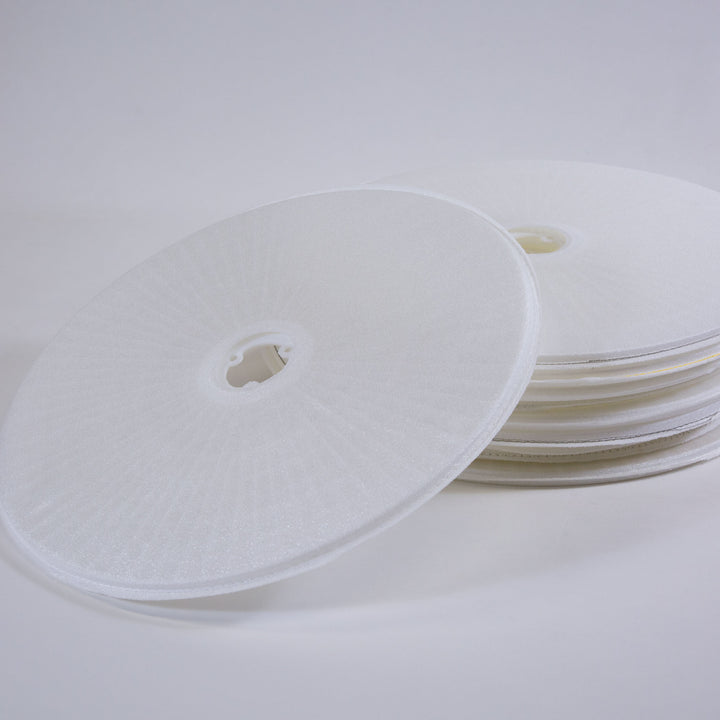 Stack of circular white filter grid discs with a central hole for pool spa filter replacement