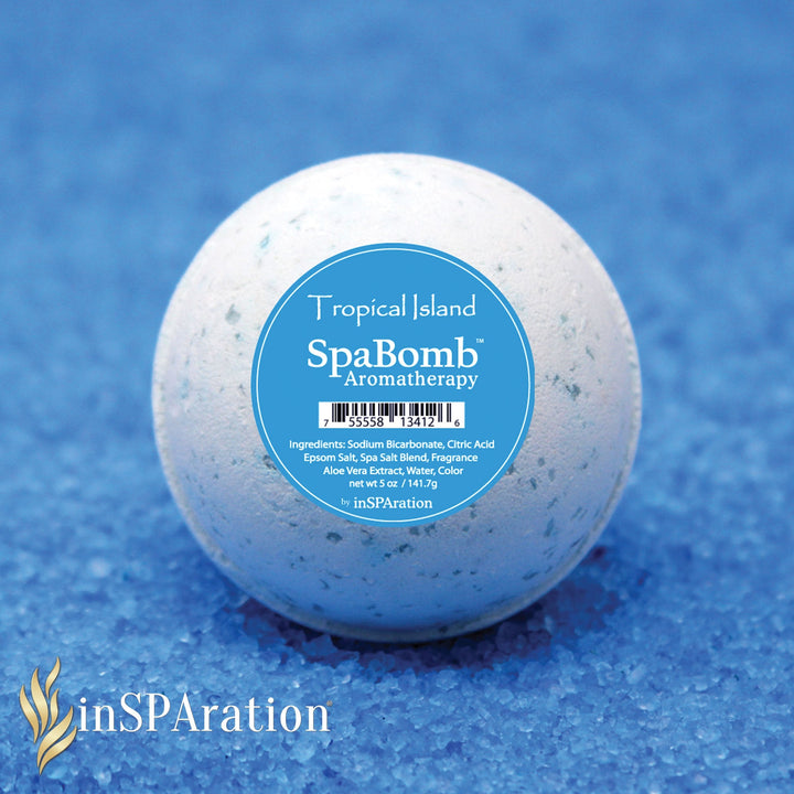 close-up of inSPAration SpaBomb Aromatherapy bath bomb with blue label on blue textured surface showing product name and ingredients