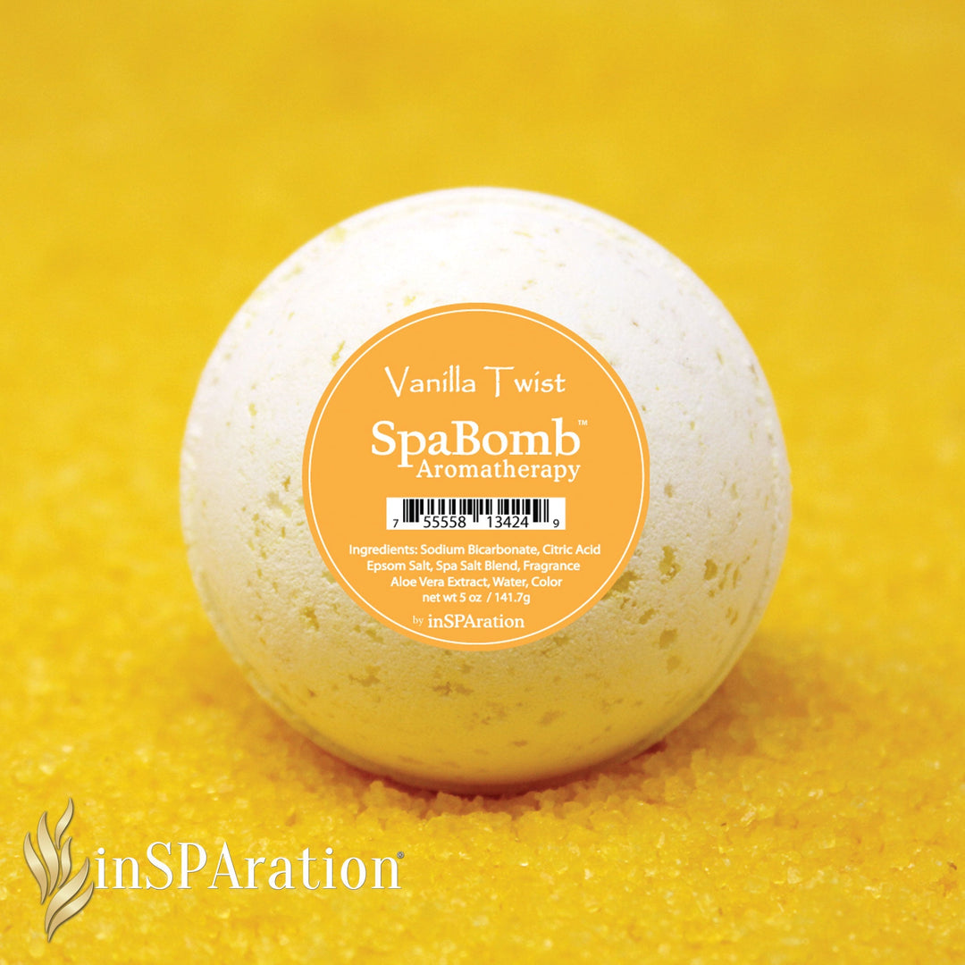 inSPAration SpaBomb Aromatherapy vanilla twist scent shown as a pale beige round bath bomb on yellow salt crystals background