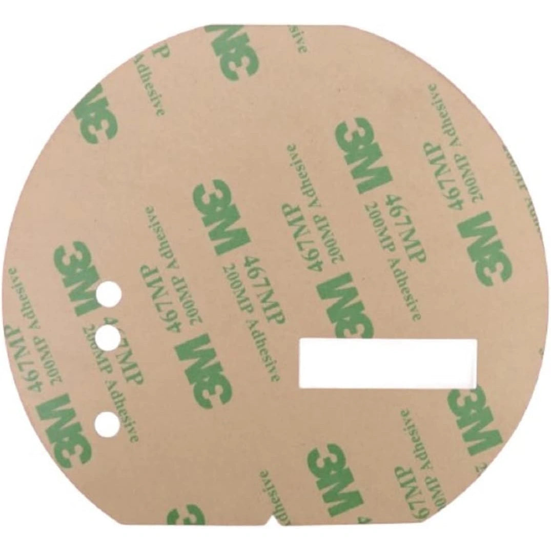 Round adhesive label with three small circular holes and one rectangular cutout with 3M branding in green on a brown background