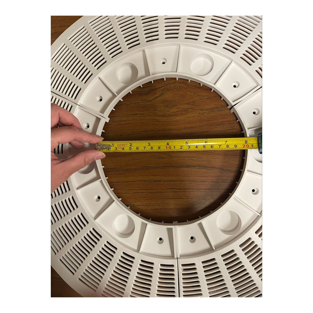 white circular pool drain outlet cover with rectangular slotted vents and central hole being measured with a tape measure