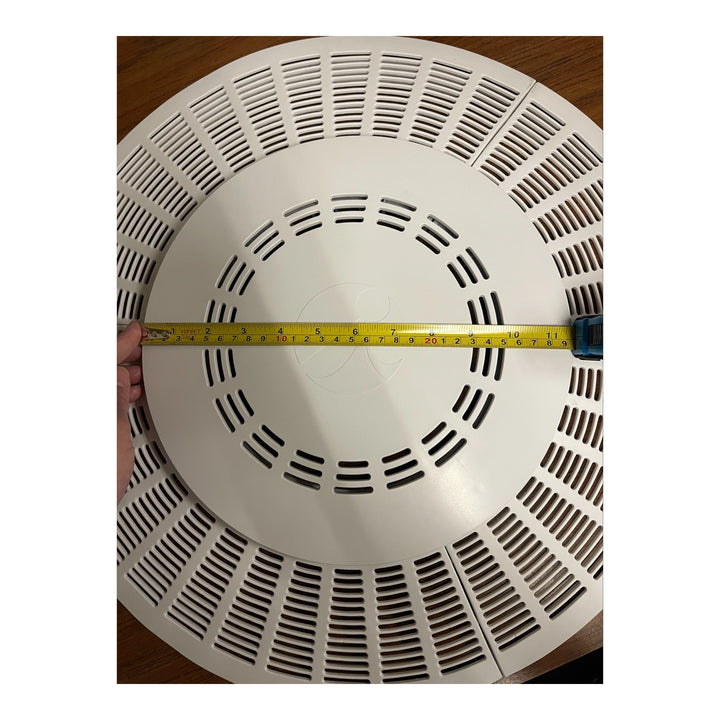 white circular pool drain outlet cover with multiple rectangular slots and a measuring tape showing its diameter